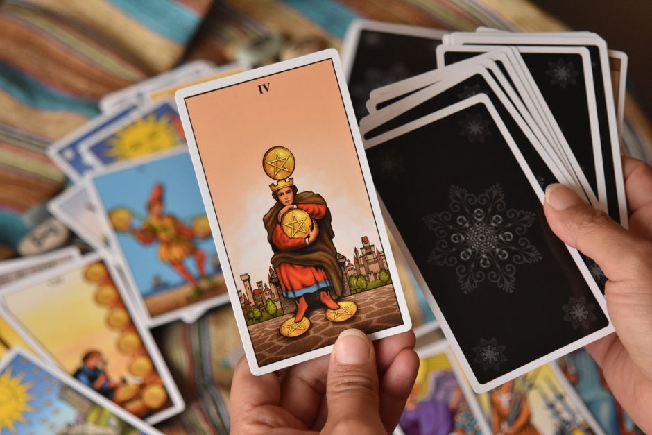 Bir tarot falı seansı sırasında bir kişinin elinde tarot kartı tutarken ve gösterirken çekilmiş yakın plan görüntüsü.