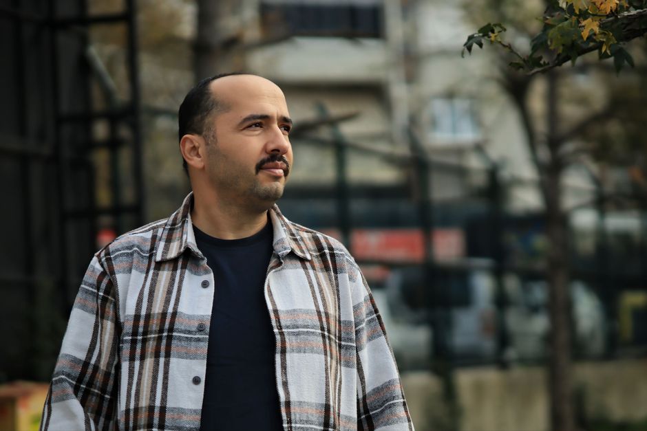 Dışarıda, kentsel bir fon önünde, düşünceli görünen ekose gömlekli bir adam. Sonbaharda çekildi.